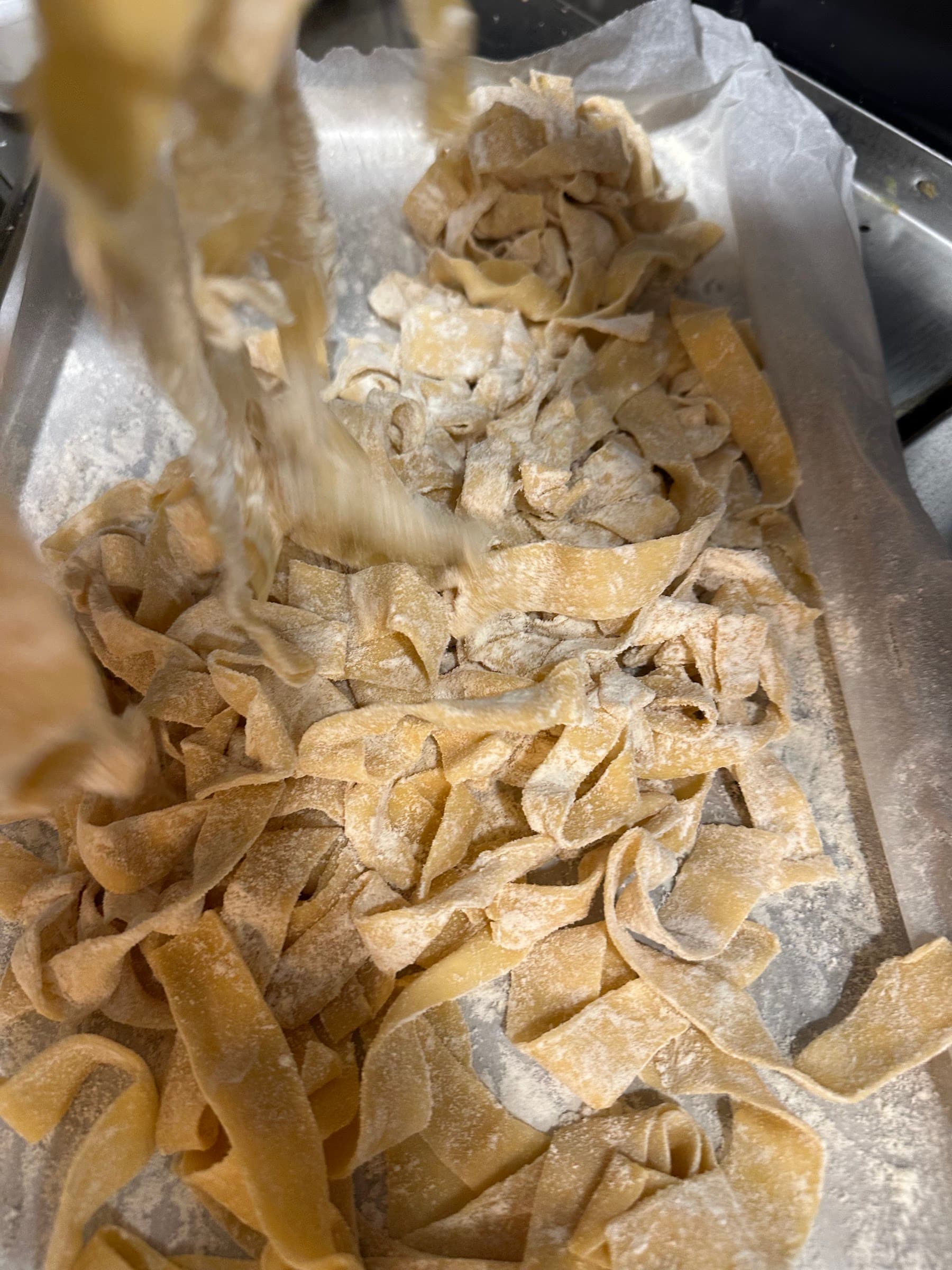 Cintas anchas de pasta fresca, enharinadas sobre una bandeja